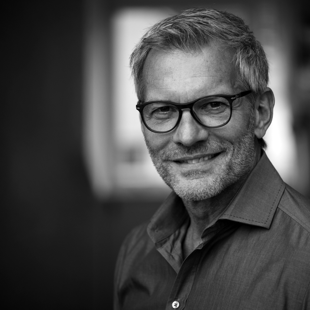 Black-and-white portrait of smiling man with glasses