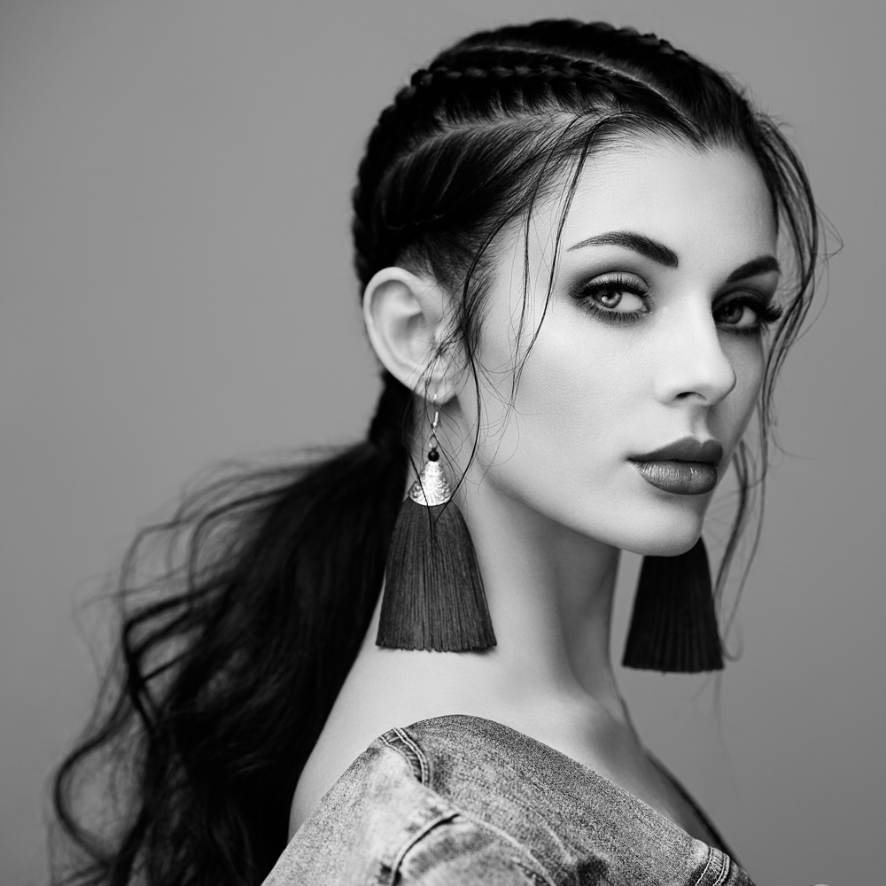 Black-and-white portrait of woman with braided hair and tassel earrings