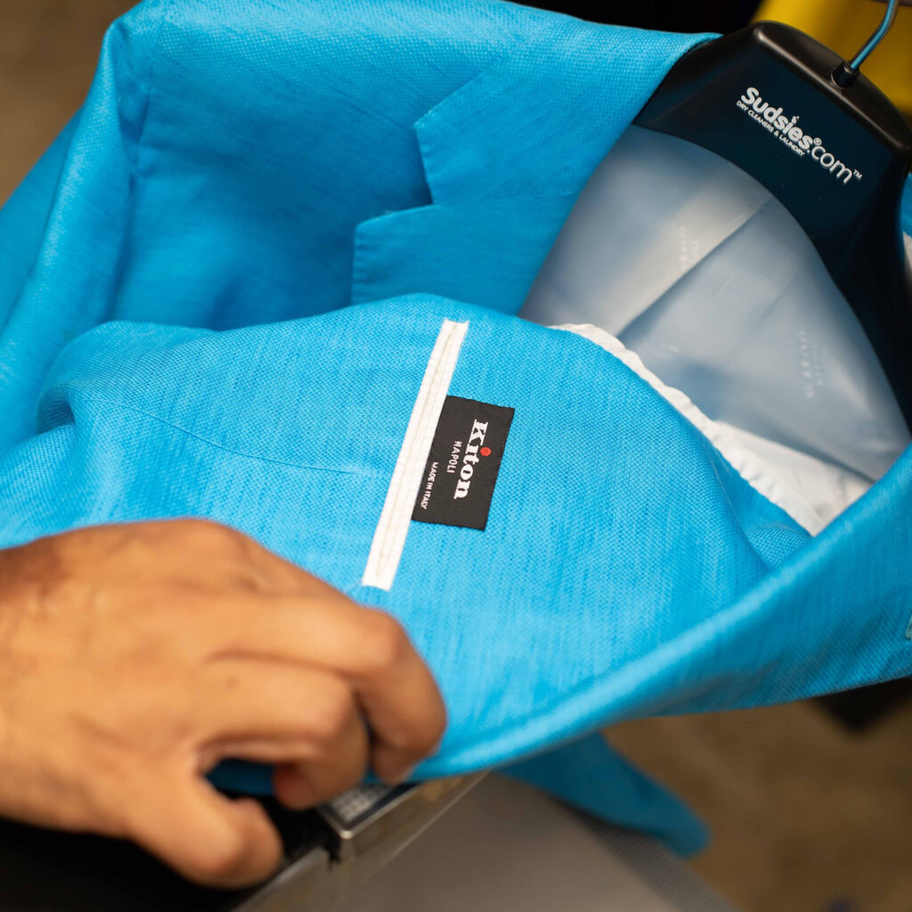 Kiton Napoli blue blazer on Sudsies hanger being inspected.