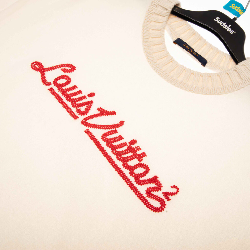 Louis Vuitton sweater with red embroidered logo on a Sudsies hanger.