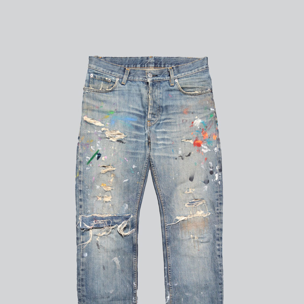 Heavily distressed jeans with paint splatters and frayed details.