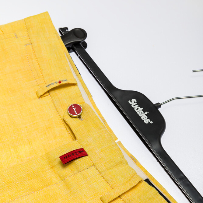 Yellow Boglioli trousers on Sudsies clip hanger, angled close-up.